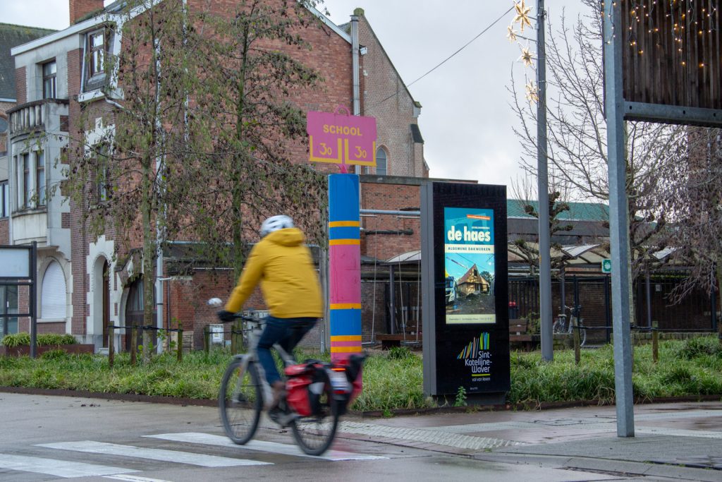 Fietsers rijdt langs een reclamezuil met een LCD-scherm.