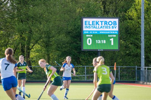Hockeyspelers op het veld naast het digitale scorebord